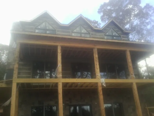 Dormers and porch framing on a large log home under construction — Roof Coating work by our crew in O Brien