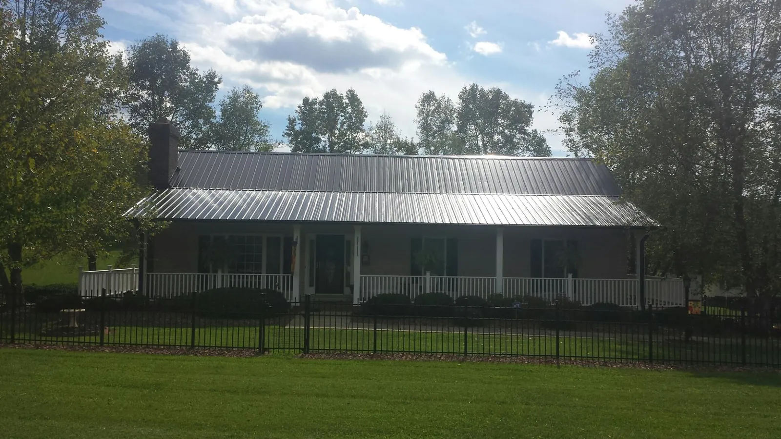 Gray metal roof on a brick ranch with a full width front porch — Gutter Guard Installation work by our crew in O Brien